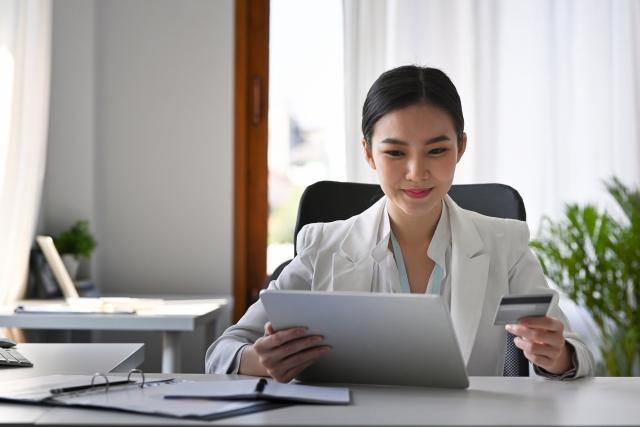 a woman holding a credit card calculating business costs