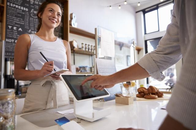 man using credit card reader in a cool coffee shop