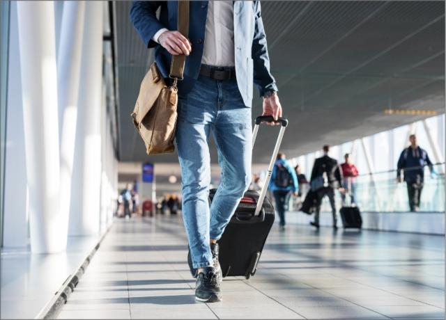 a man walks through a clean terminal with a carryon suitcase and a messenger bag