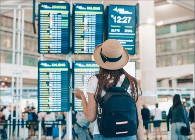 Woman stands in airport checking for her flight time in a busy terminal