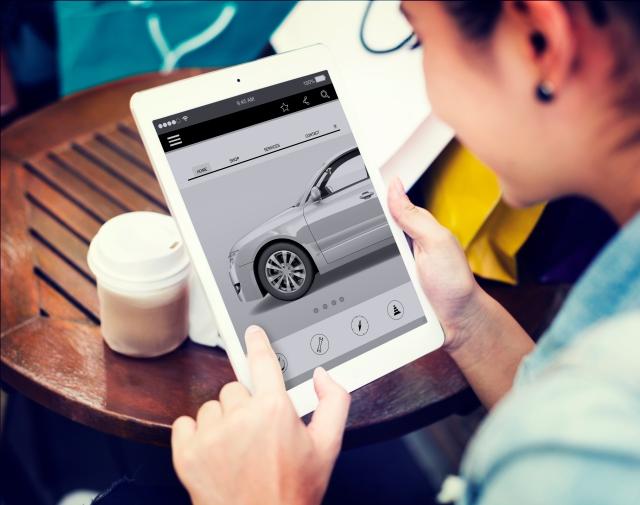 Customer shopping for a car on a tablet, using modern digital retailing app to customize vehicle online before visiting dealership.