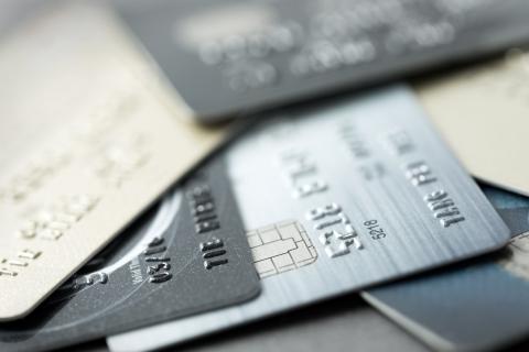 Multiple credit cards with EMV chip technology stacked on a light surface with laptop keyboard visible in background