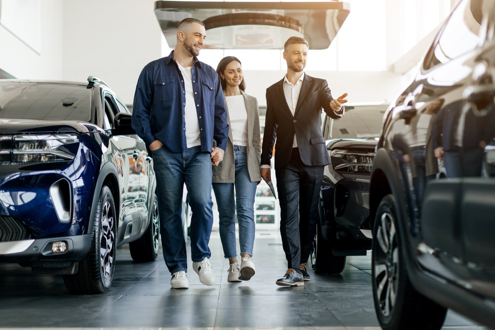 Couple walking through car showroom with salesperson