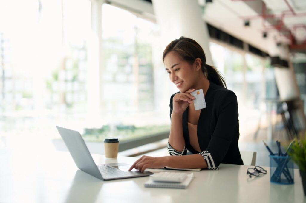 Businesswoman at laptop holding a credit card, smiling