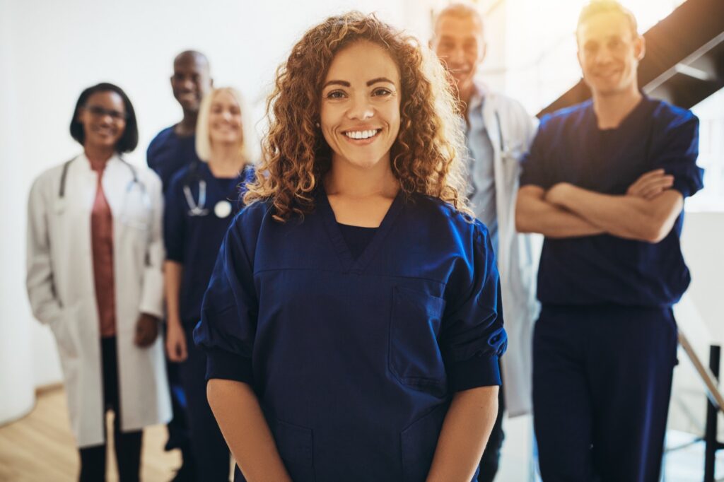 Smiling team of healthcare professionals (scrubs, lab coats, stethoscopes)