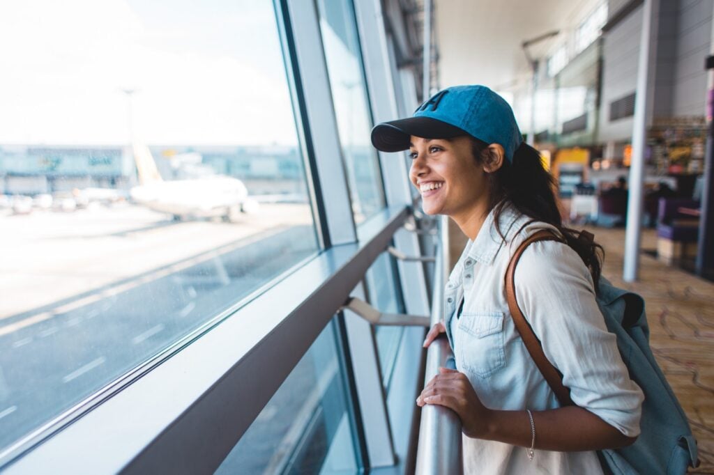 Young traveler at an airport window watching planes on the tarmac