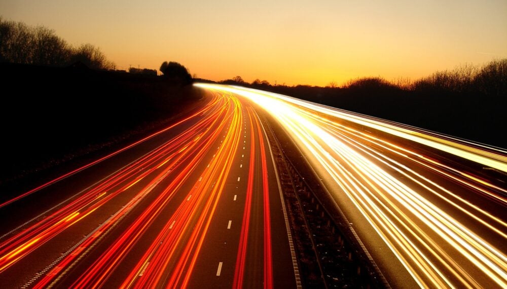 Dynamic light trails illuminate a highway at dusk