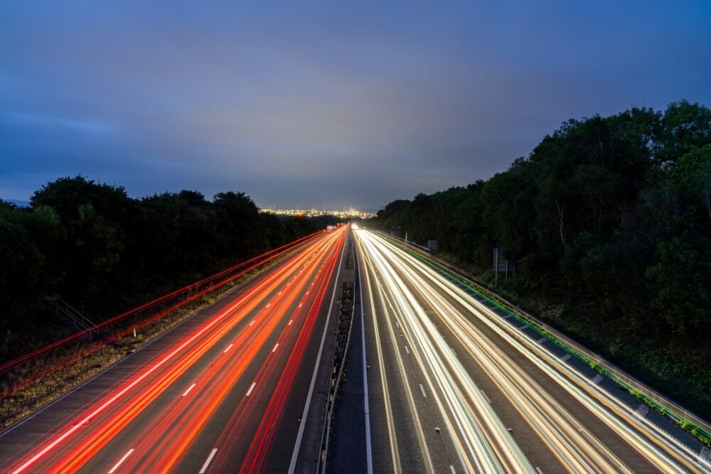 Light trails illuminating highway at dusk with city lights in background