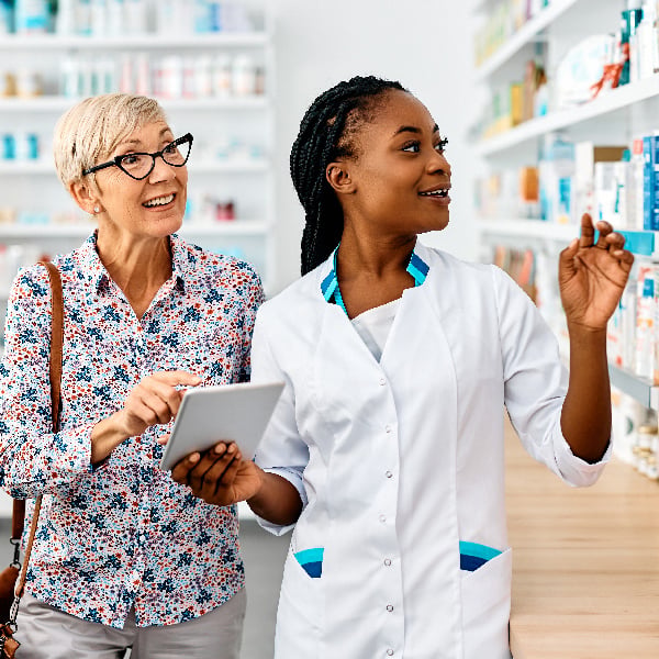 Pharmacist with a customer holding a tablet and searching for a product.