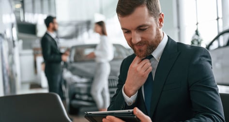 Man in car dealership holding a tablet.